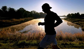 silloutte of a person running in front of a pond