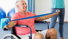 An older adult does exercises in a wheelchair.