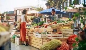 Person examines produce while shopping at farmers market