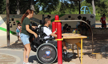 A park patron plays at the elevated sand table while others enjoy the shaded sand box and custom designed learning wall. A park patron plays at the elevated sand table while others enjoy the shaded sand box and custom designed learning wall.